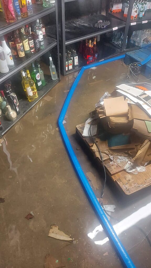 Flooded bar area with damaged drainage pipe after burst, requiring urgent repair.