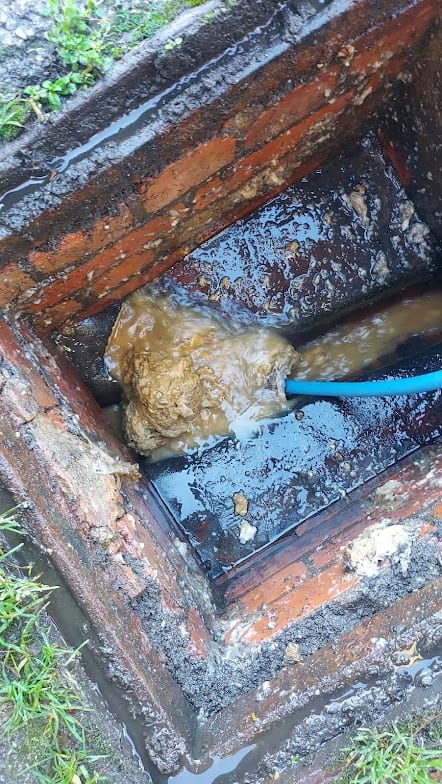 Drainage system repair in progress at a brick manhole.