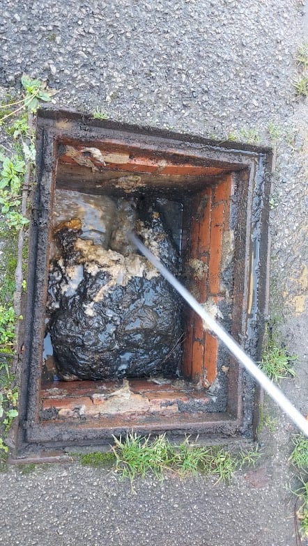 Open drainage inspection chamber with debris and blockages.