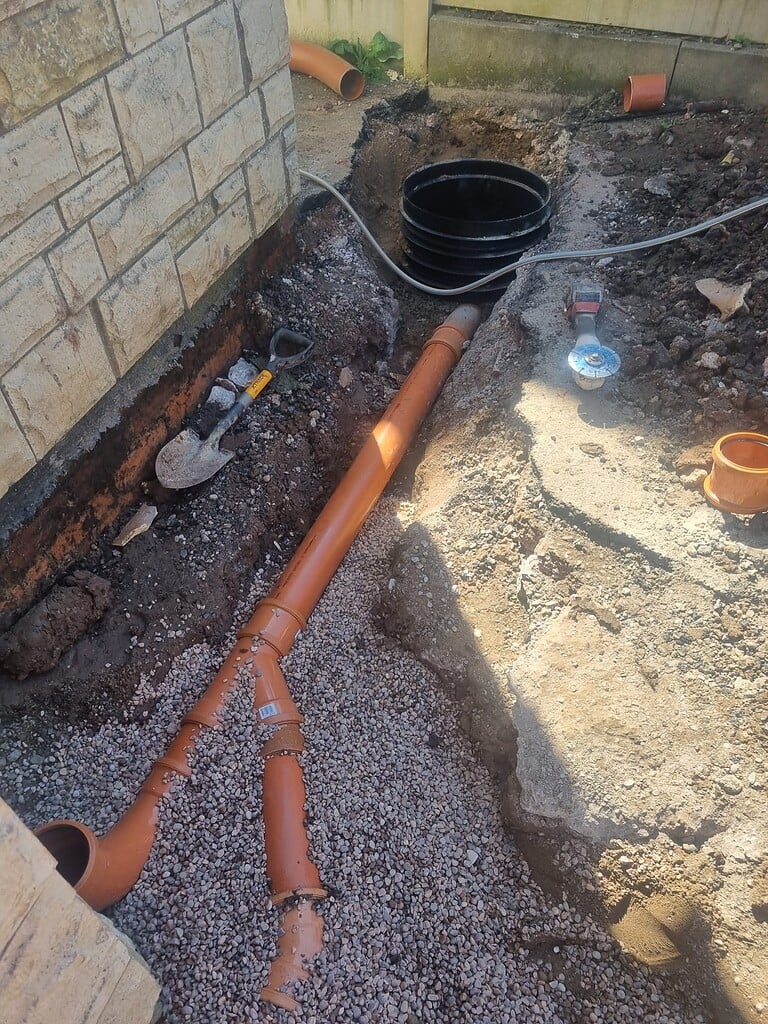 Underground drainage pipe installation with orange PVC pipes and fittings for effective property dra.