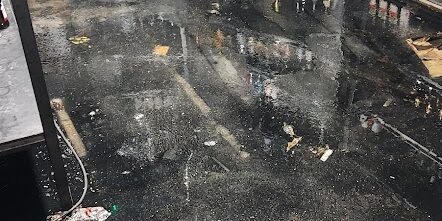 Flooded liquor store floor caused by plumbing failure, with spilled bottles and water damage.